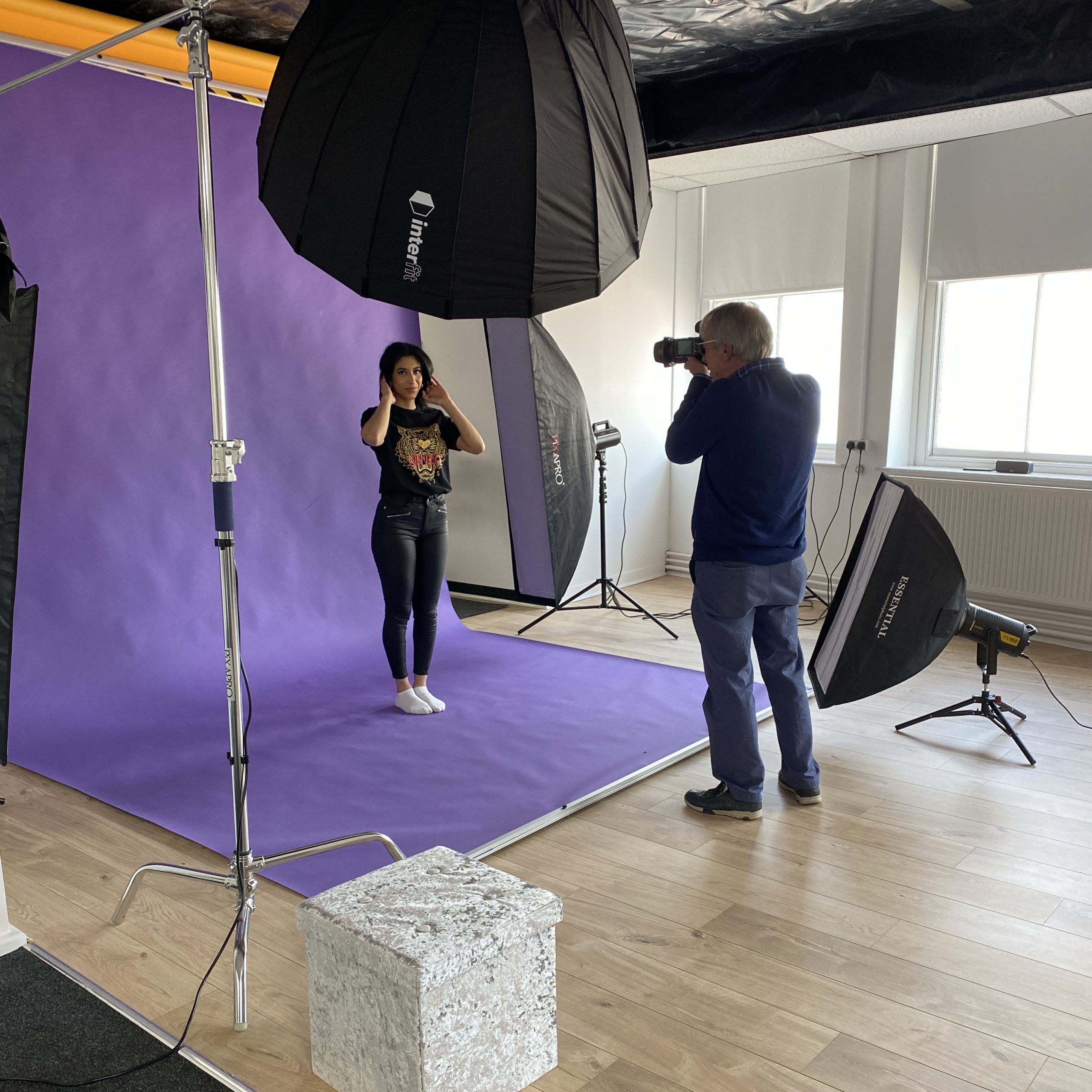 Photographer photographing model on purple backdrop